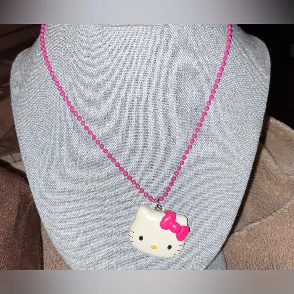 Hello Kitty :Kitty face slightly angled on a bight pink beaded necklace blue bow